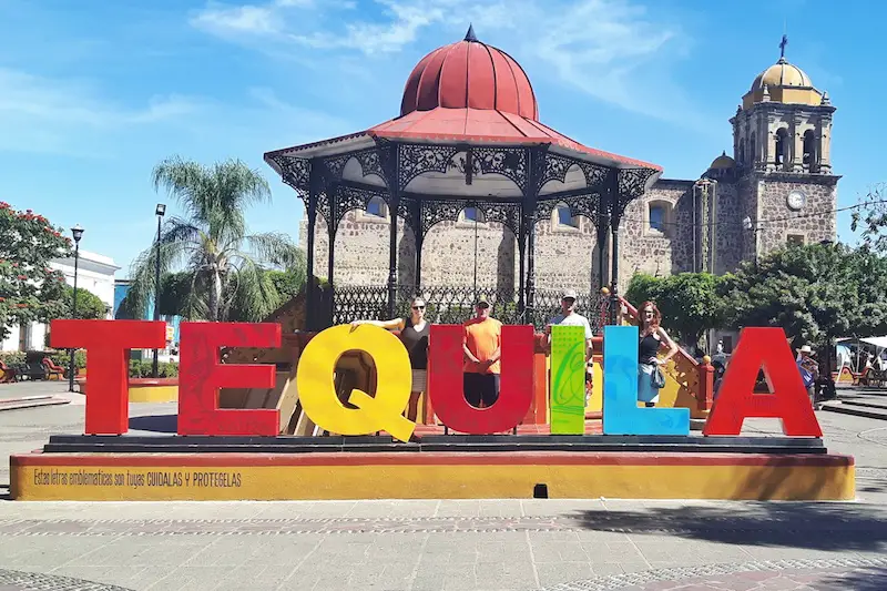 People standing behind the colourful 'Tequila' sign in Jalisco, Mexico.