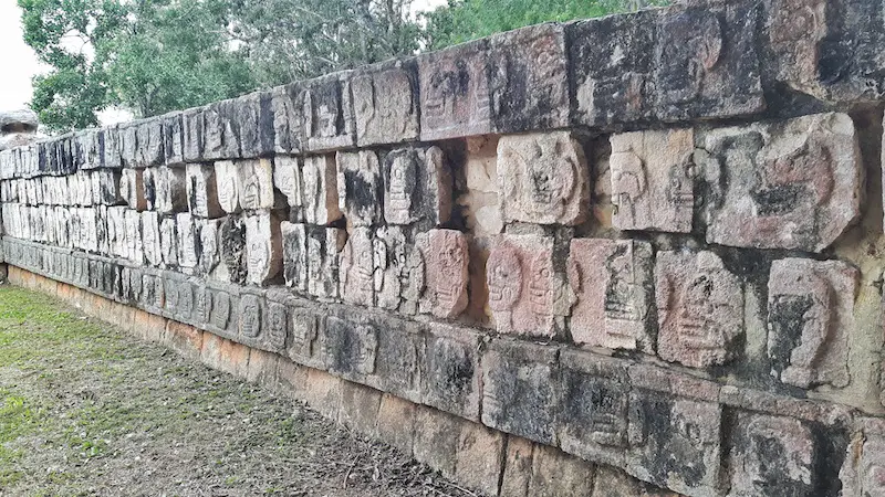 Ancient stone wall with a carving of a skull on each stone at Chichen Itza, Mexico