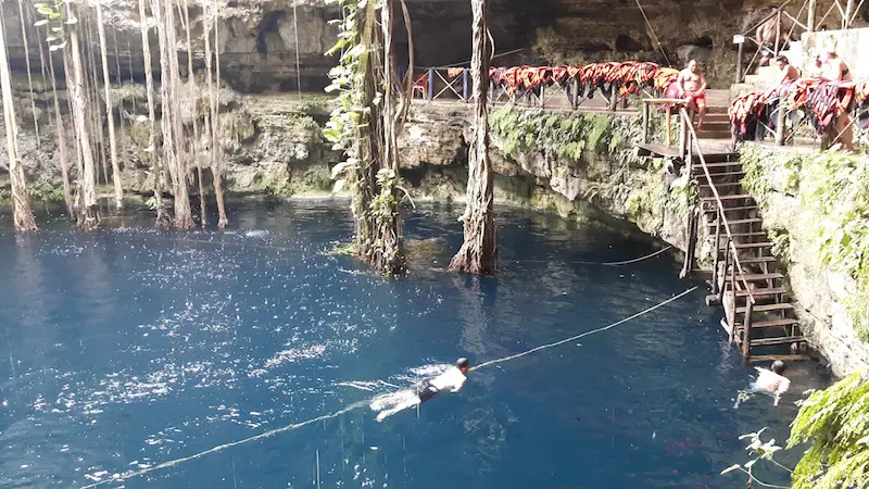 Swimming to the stairs in Cenote San Lorenzo Oxman with a rope for help in Mexico.