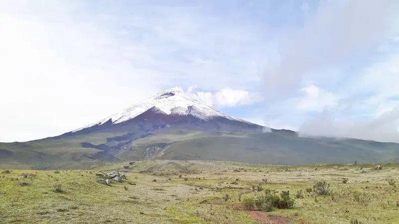 Snow-capped Cotopaxi volcano with steam rising from top in Ecuador.