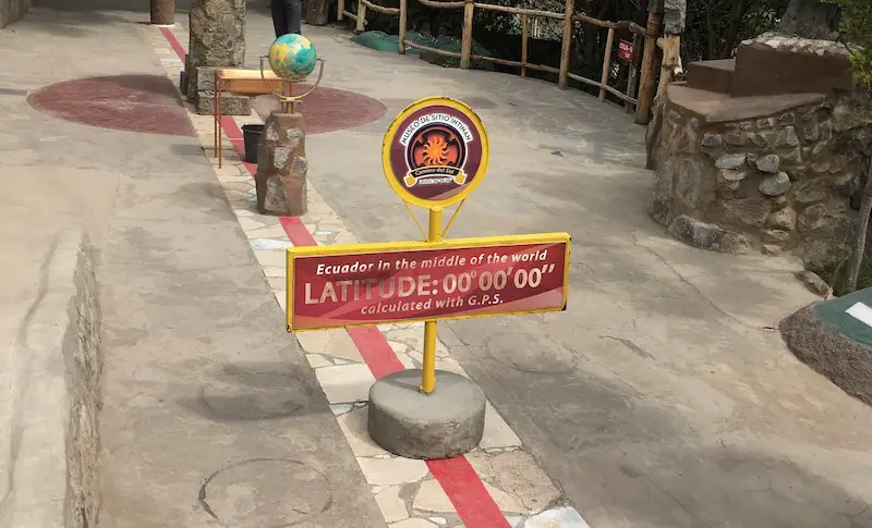 Red painted line and a sign to show the equator line in Ecuador.