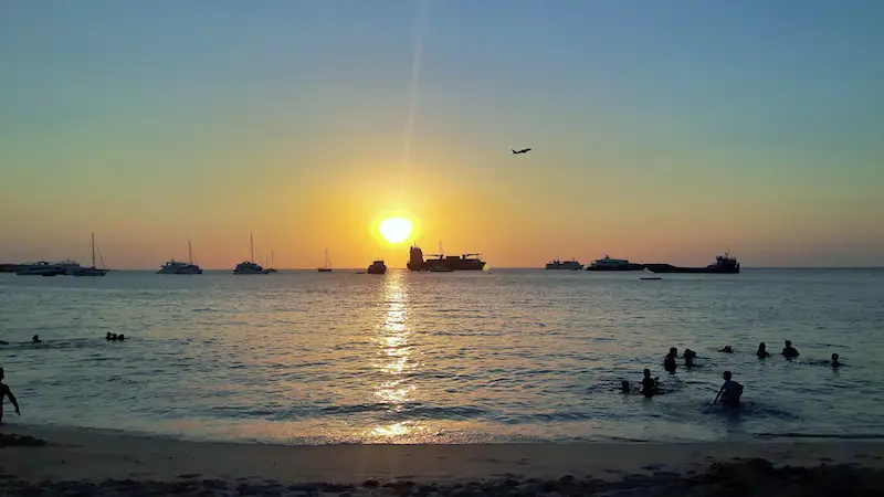 sunset on Galapagos beach with boats and a plane taking off, Ecuador.