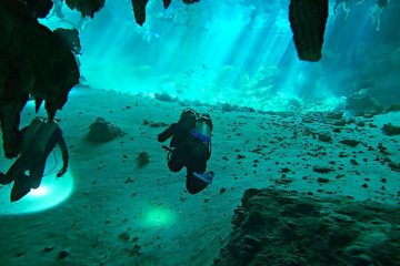 Divers in clear blue water in Cenote Dos Ojos, Mexico.
