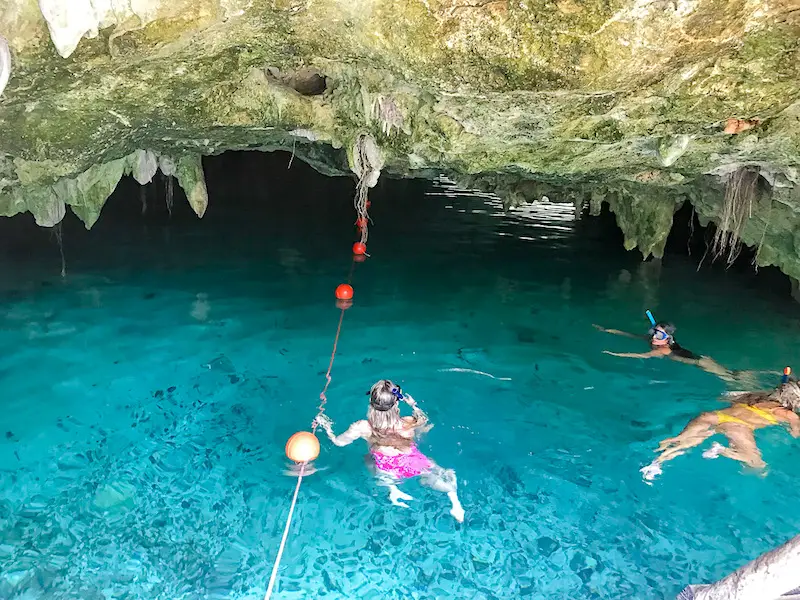 People swimming inside the clear blue water of Gran Cenote, Mexico.