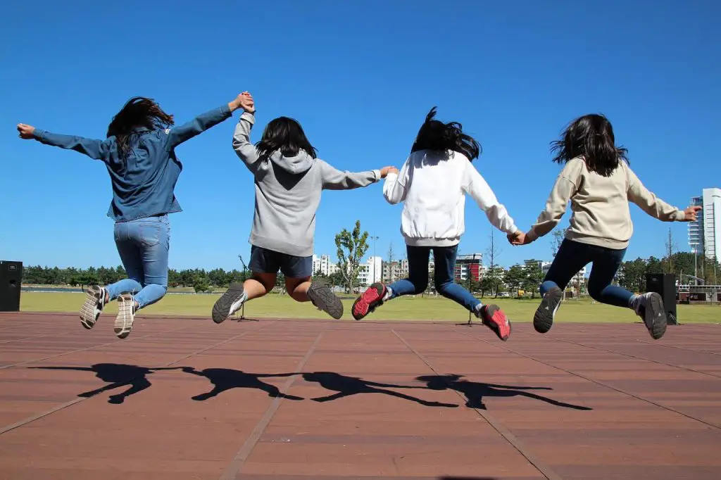 Girls jumping on a school track enjoying outside fun end of the year activities.